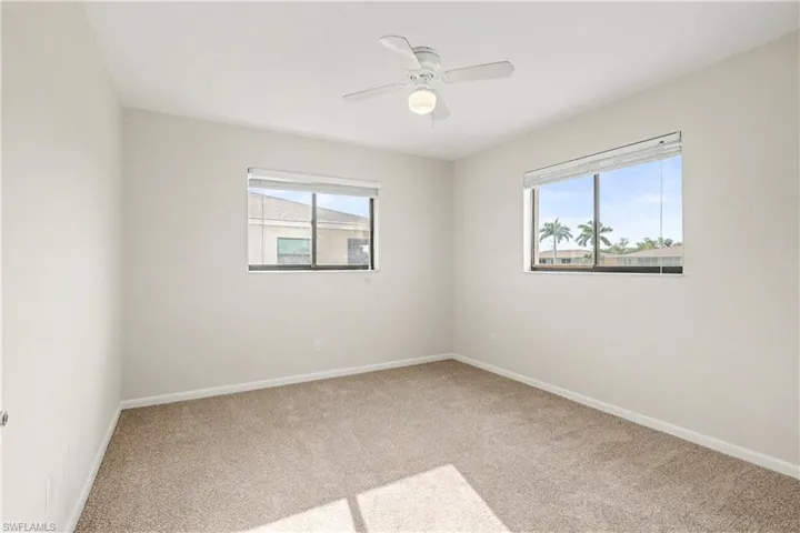 Spare room featuring light colored carpet, healthy amount of natural light, and ceiling fan