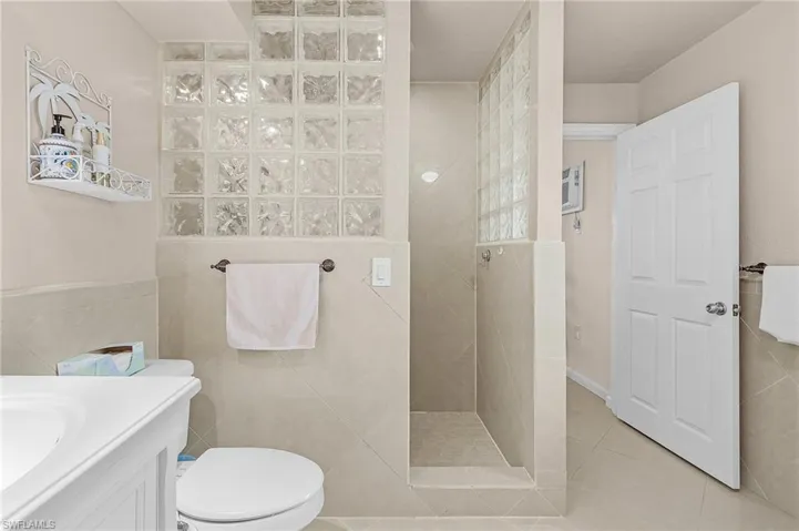 Bathroom with tile patterned flooring, toilet, tile walls, tiled shower, and vanity