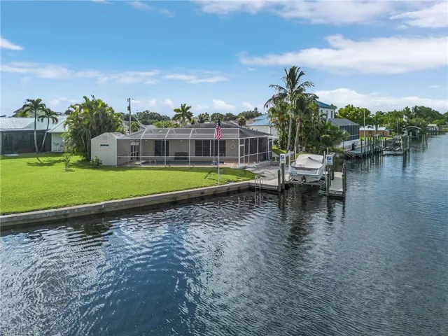 View of dock with a lanai, a yard, and a water view