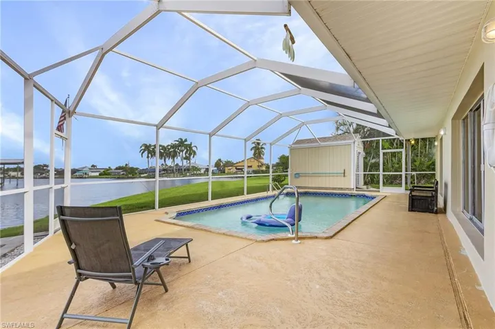 View of swimming pool with a water view, a lanai, and a patio