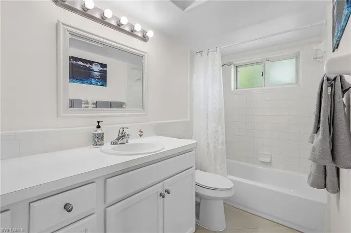 Full bathroom with vanity, toilet, tile patterned floors, and shower / bath combo with shower curtain