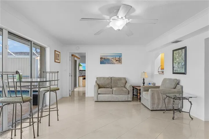Living room with ceiling fan, light tile patterned floors, and ornamental molding