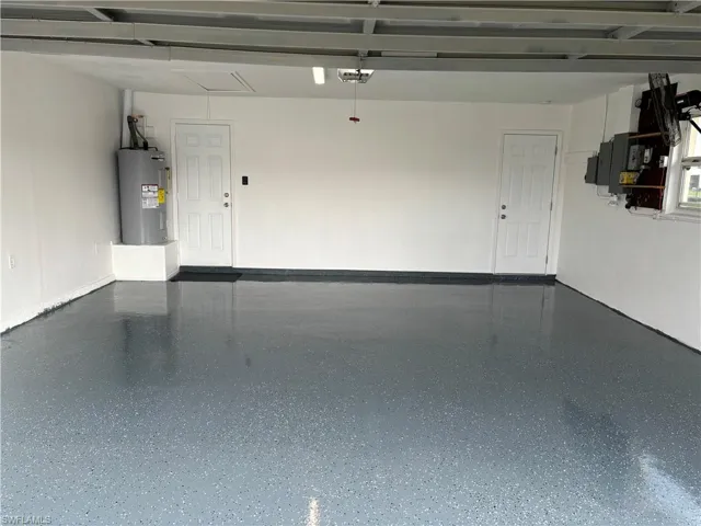 Garage featuring electric water heater and a garage door opener