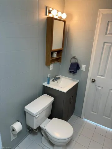 Bathroom featuring vanity, toilet, tile walls, and tile patterned flooring