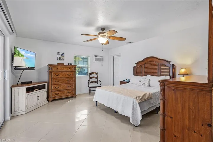 Bedroom featuring ceiling fan, an AC wall unit, and light tile patterned flooring
