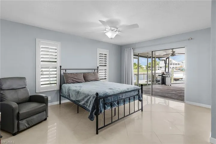 Bedroom featuring a textured ceiling, access to exterior, ceiling fan, and multiple windows