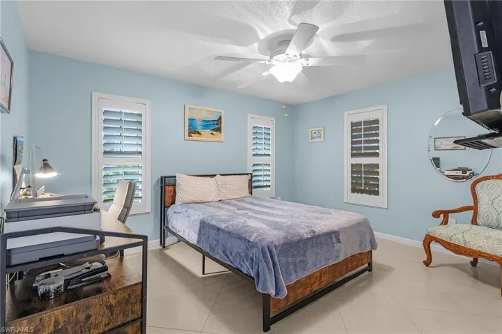 Bedroom with ceiling fan, light tile patterned floors, and a textured ceiling