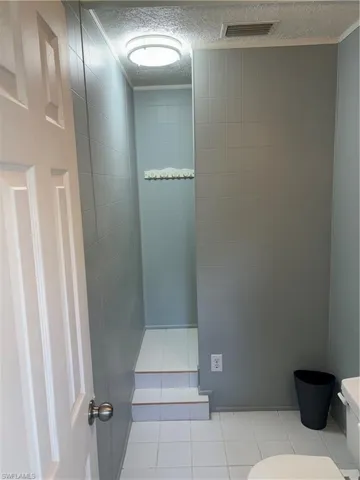 Bathroom featuring a textured ceiling, toilet, and tile patterned flooring