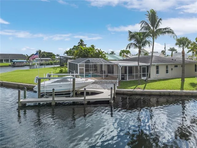 View of dock with a water view, a lawn, and glass enclosure