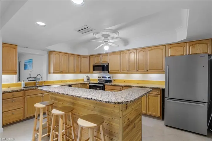 Kitchen featuring a center island, stainless steel appliances, sink, ceiling fan, and a breakfast bar