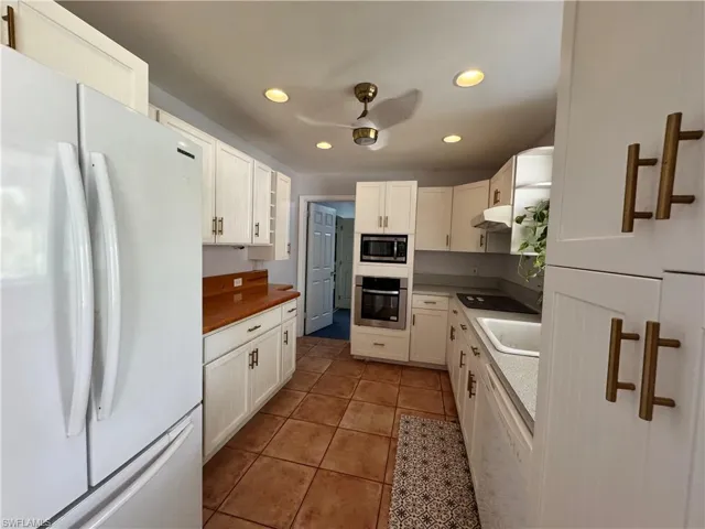 Kitchen featuring recessed lighting, under cabinet range hood, white cabinetry, and stainless steel appliances