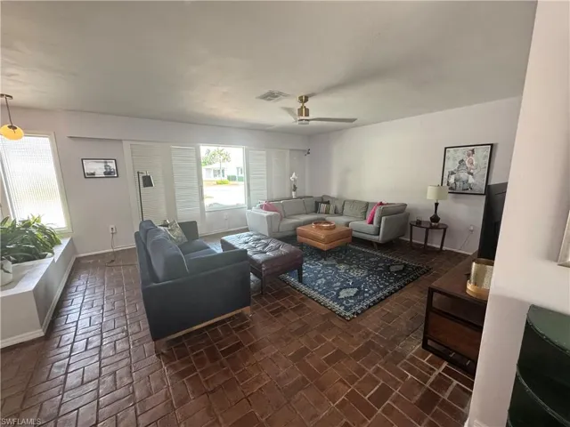 Living area featuring brick floor, visible vents, and a healthy amount of sunlight