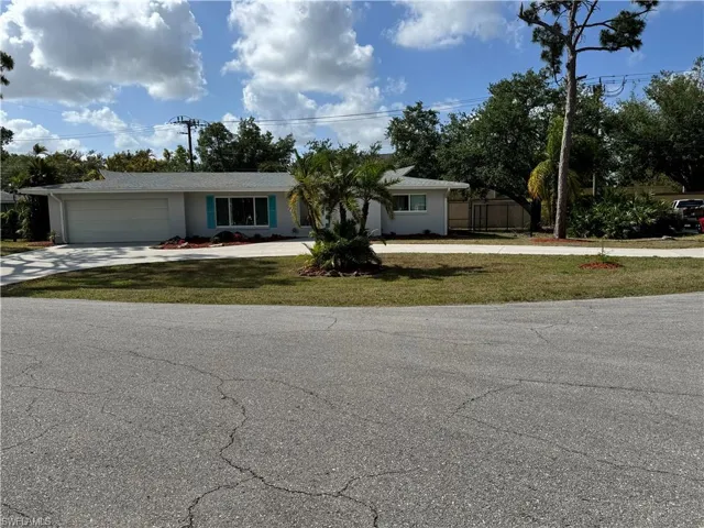Ranch-style house with concrete driveway, an attached garage, fence, a front yard, and stucco siding