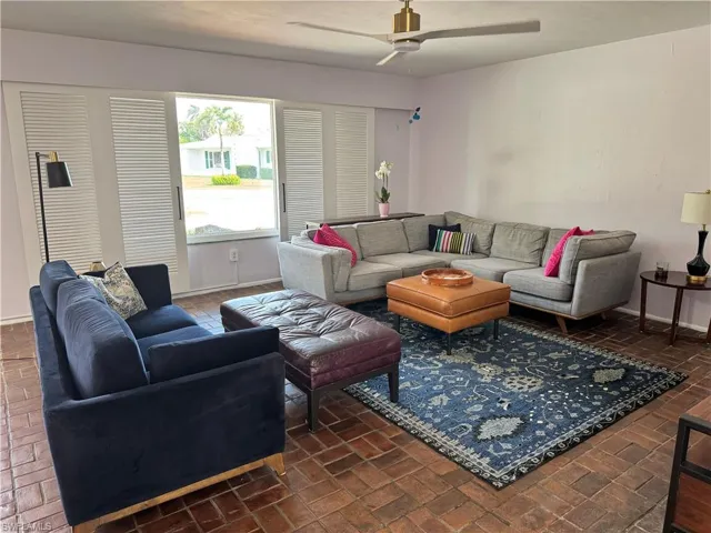 Living area featuring brick floor, baseboards, and ceiling fan