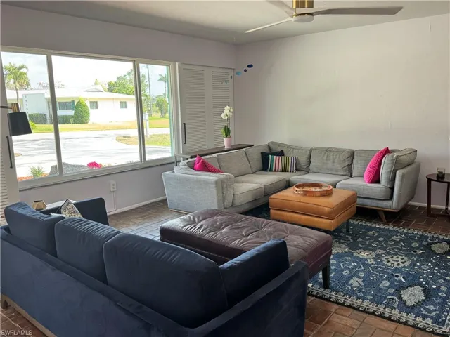 Living area with brick floor, baseboards, and ceiling fan