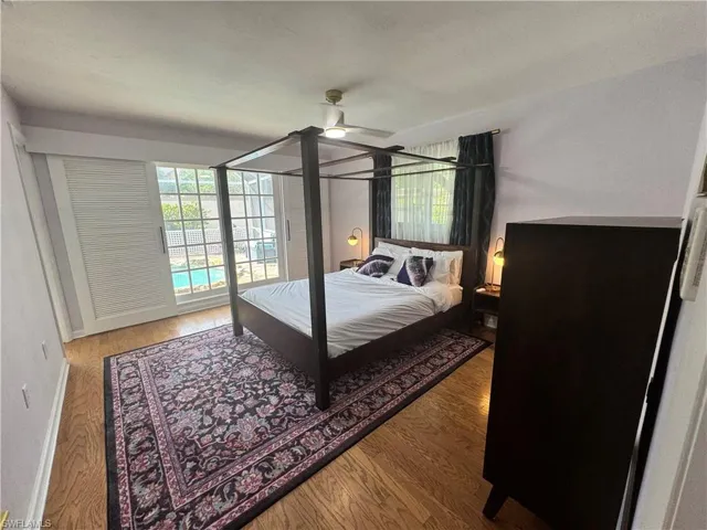 Bedroom with wood finished floors, baseboards, ceiling fan, and access to exterior