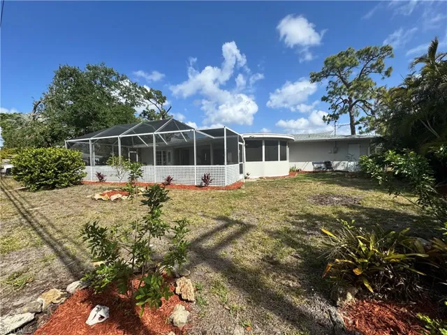 Back of property featuring a lanai and a yard