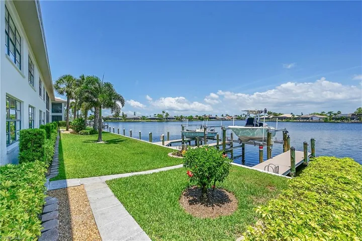 Dock area featuring boat lift, a lawn, and a water view