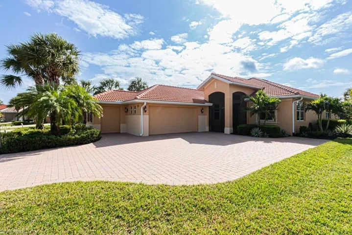 Mediterranean / spanish home featuring a tiled roof, stucco siding, a front yard, an attached garage, and driveway