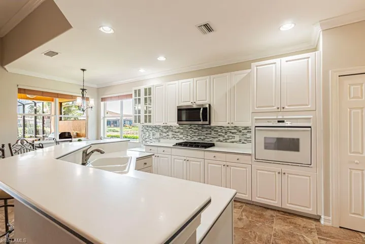 Kitchen with white oven, visible vents, stainless steel microwave, and a sink