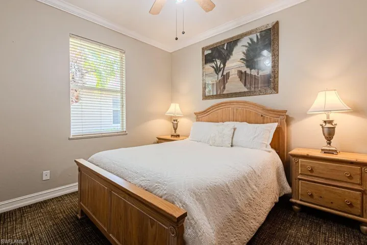 Bedroom featuring dark colored carpet, baseboards, ornamental molding, and ceiling fan