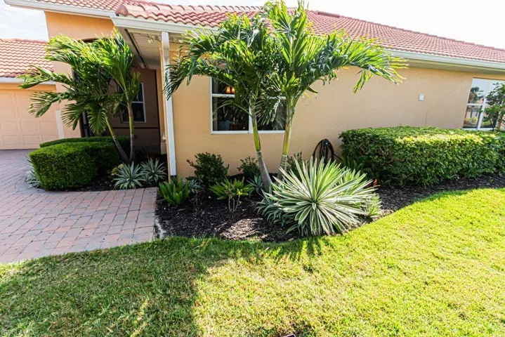 View of side of home featuring a tiled roof, a garage, stucco siding, and a yard