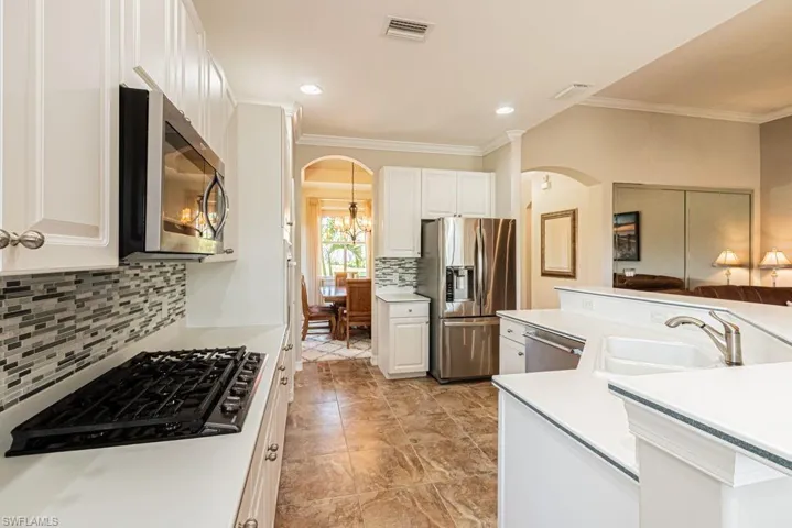 Kitchen featuring arched walkways, visible vents, appliances with stainless steel finishes, a sink, and decorative backsplash
