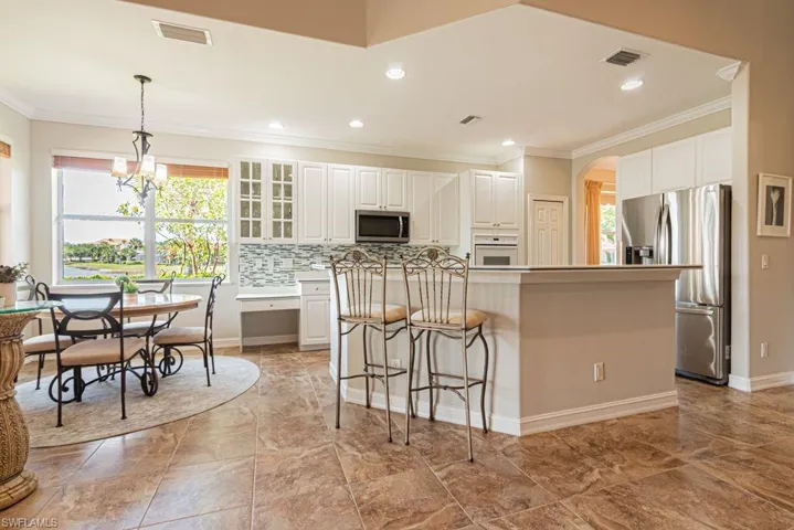 Kitchen with ornamental molding, a kitchen island, white cabinets, visible vents, and appliances with stainless steel finishes