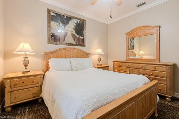 Bedroom featuring crown molding, dark carpet, ceiling fan, and visible vents