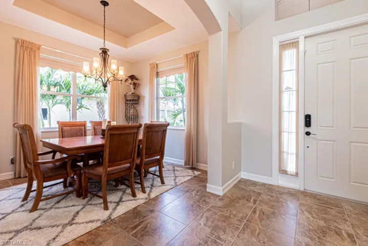 Dining room with arched walkways, a notable chandelier, baseboards, and a raised ceiling