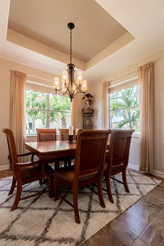 Dining area featuring a raised ceiling, an inviting chandelier, baseboards, and stone finish flooring