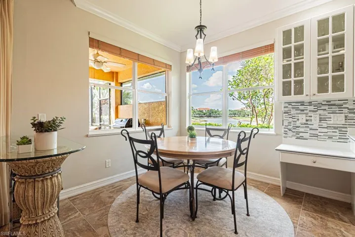 Dining space with stone finish flooring, a notable chandelier, baseboards, and crown molding