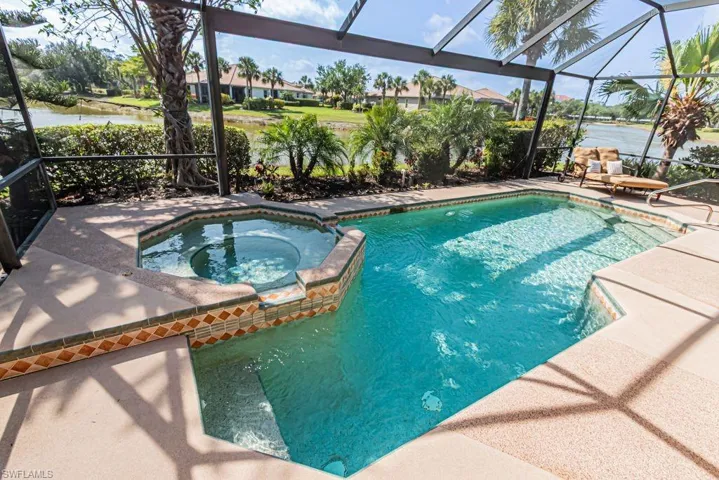 View of swimming pool featuring a water view, a patio area, a pool with connected hot tub, and a lanai