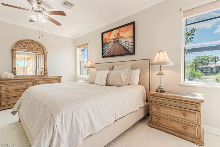 Bedroom with crown molding, visible vents, multiple windows, and light colored carpet