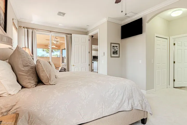 Bedroom with access to outside, arched walkways, ornamental molding, visible vents, and carpet flooring