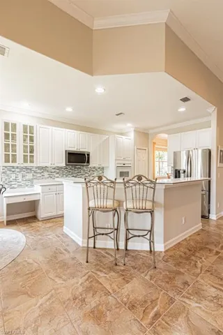 Kitchen featuring stainless steel appliances, a breakfast bar area, visible vents, and ornamental molding