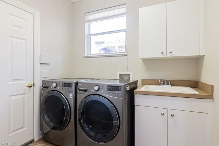 Washroom featuring a sink, cabinet space, and washing machine and dryer