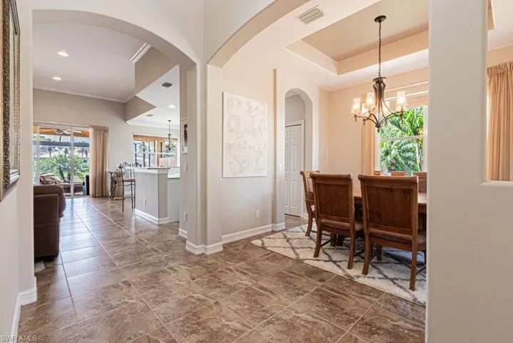 Dining room featuring visible vents, baseboards, arched walkways, a notable chandelier, and crown molding