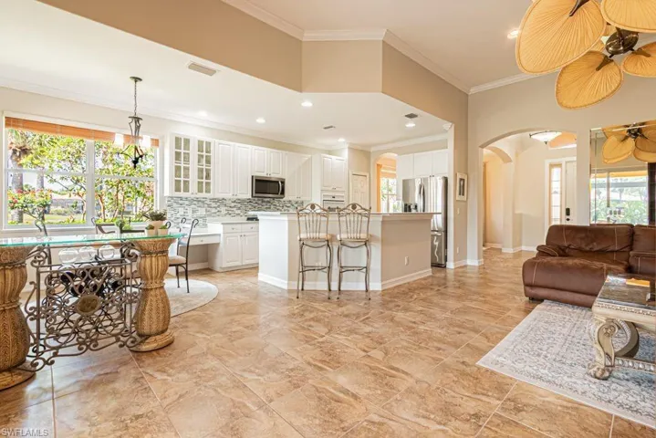 Living area featuring arched walkways, plenty of natural light, visible vents, and ornamental molding