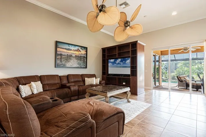 Living room featuring light tile patterned floors, visible vents, baseboards, and crown molding