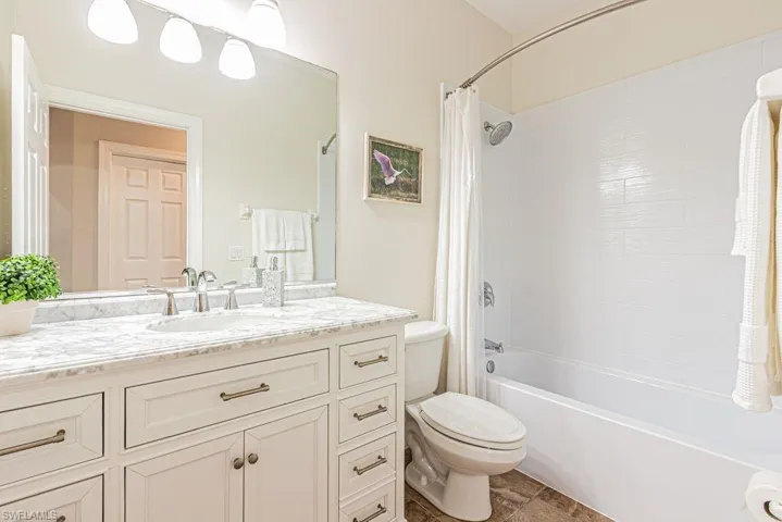 Bathroom with vanity, shower / bath combination with curtain, and toilet