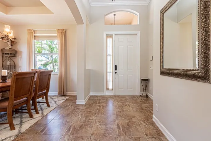 Foyer entrance with arched walkways, baseboards, and ornamental molding