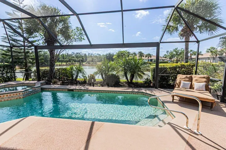 View of pool with a patio area, glass enclosure, a water view, and a pool with connected hot tub
