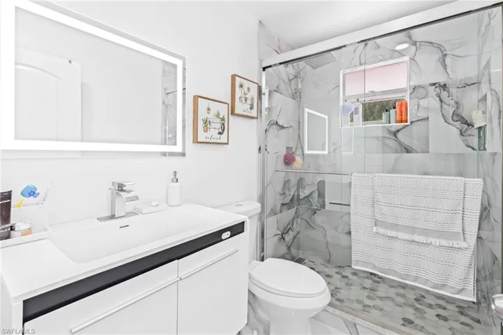 Bathroom featuring a marble finish shower and vanity