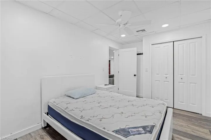 Bedroom with a closet, a paneled ceiling, light wood-style floors, a ceiling fan, and recessed lighting