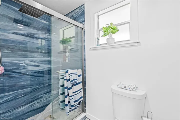 Bathroom featuring a marble finish shower and toilet