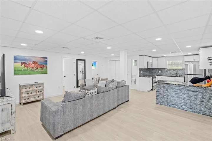 Living area featuring light wood finished floors, a paneled ceiling, and recessed lighting