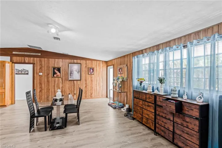 Dining area featuring lofted ceiling, wooden walls, and light wood-type flooring