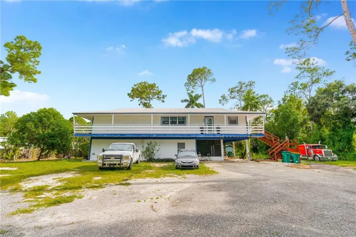 View of front of property featuring driveway, a wooden deck, and stairway
