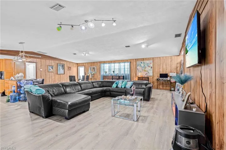 Living area featuring lofted ceiling, wooden walls, and light wood-style floors